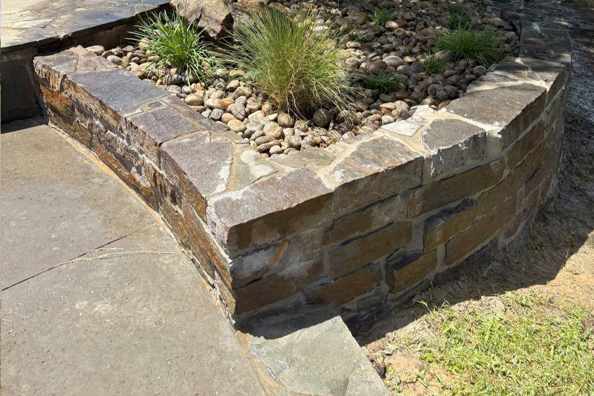 Stone retaining wall with concrete repair and landscaping accents, showcasing durable hardscape design – Hood Lawn Care and Services.