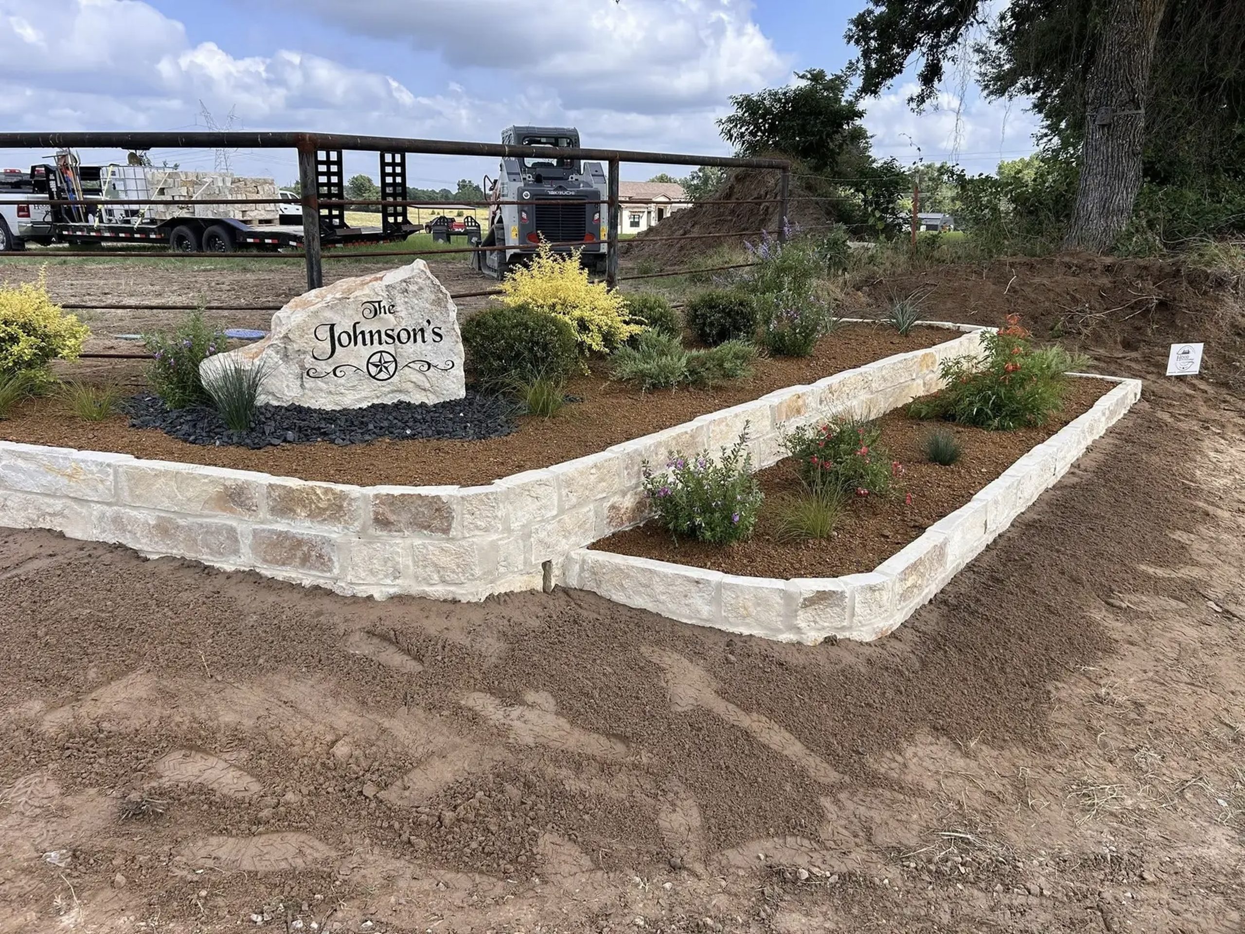 Custom stone landscape bed with decorative plants and engraved family rock – professional landscaping by Hood Lawn Care